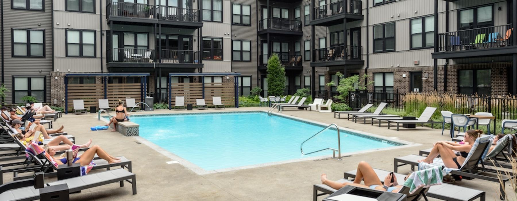 a group of people sitting around a pool in front of a building