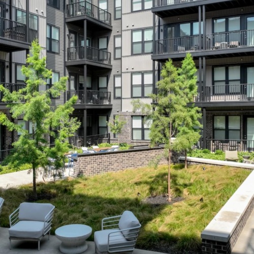 Where comfort and convenience meet a courtyard with chairs and tables and trees in front of a building